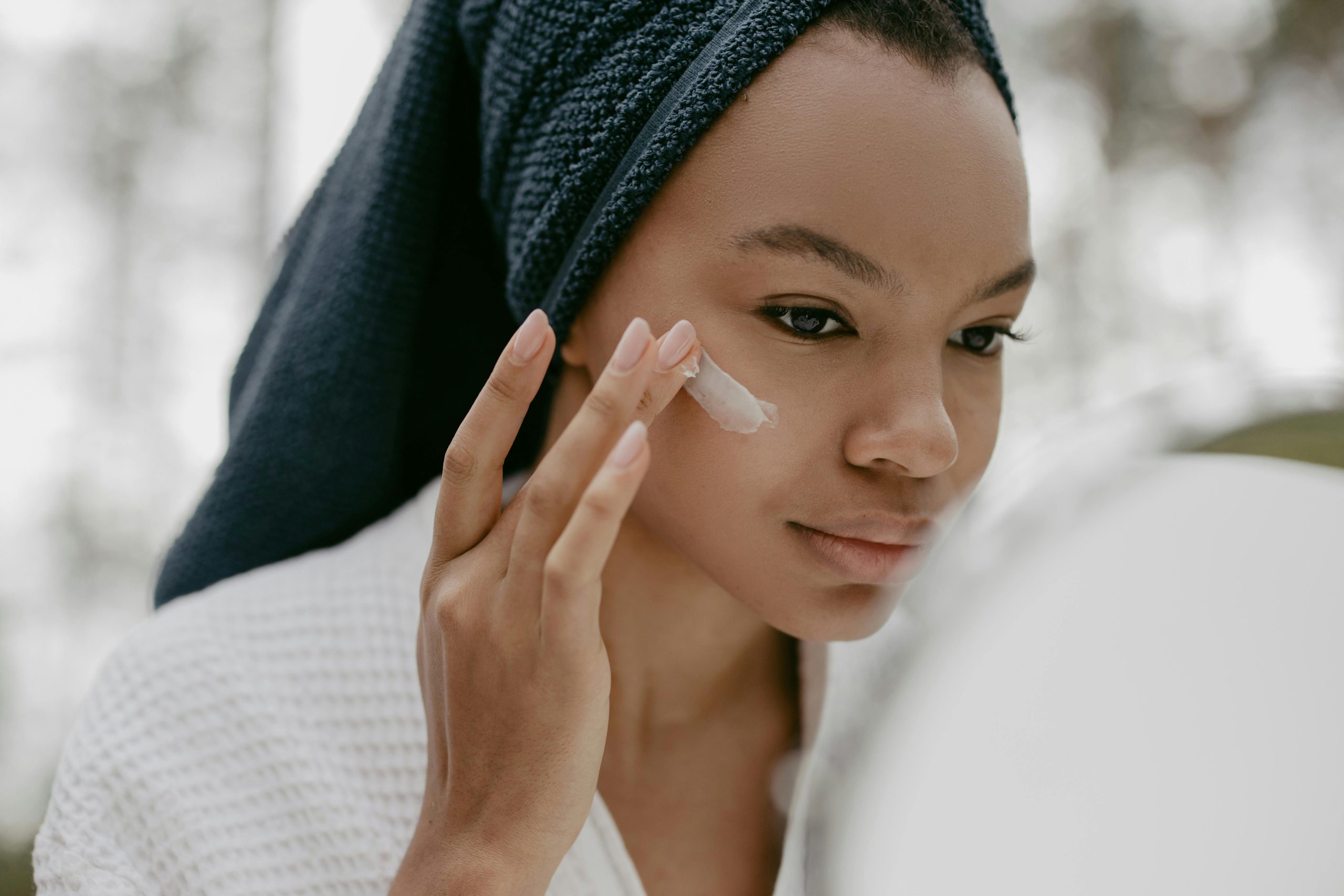 Femme appliquant de la crème sur son visage avec ses doigts