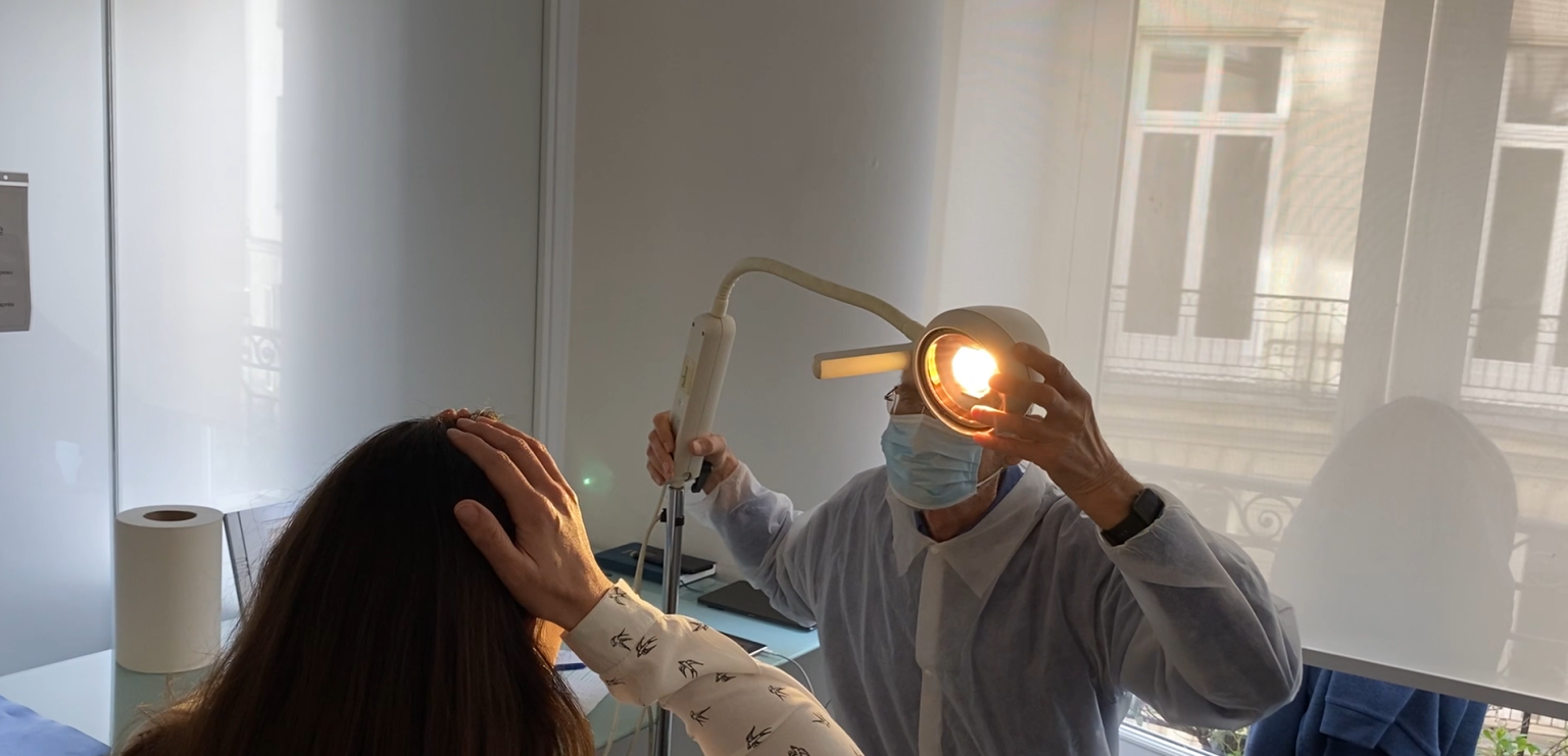Professionnel en blouse examinant un patient avec un lampe